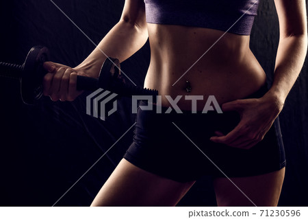 Slim athletic woman Holding dumbbell in the hand on black Slim athletic woman Holding dumbbell in the hand on black 71230596