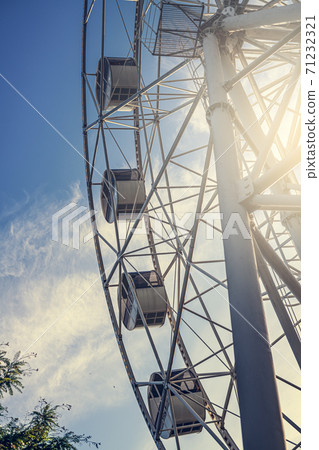 Gray or white metal ferris wheel with closed passenger cabins close-up in the amusement park Gray or white metal ferris wheel with closed passenger cabins close-up in the amusement park 71232321