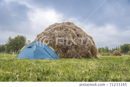 Tent on the field with mowed grass next to a haystack in autumn Tent on the field with mowed grass next to a haystack in autumn 71233165