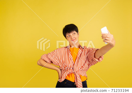 Senior woman isolated on yellow background. Tech and joyful elderly lifestyle concept 71233194