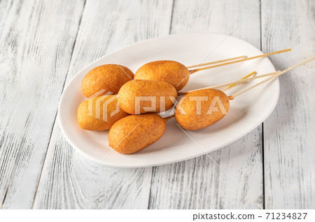 Corn dogs on white serving plate 71234827