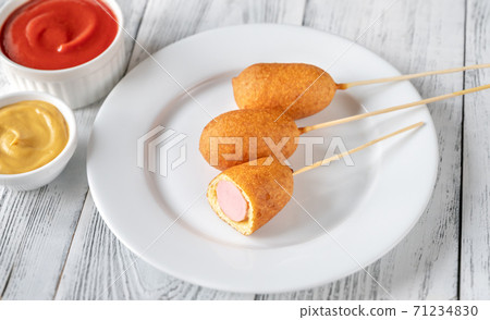 Corn dogs on white serving plate 71234830