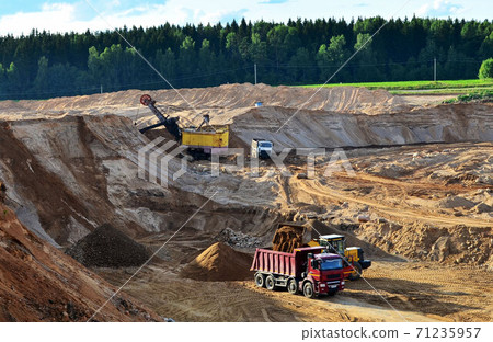 Wheel front-end loader loads sand into a dump truck. Wheel front-end loader loads sand into a dump truck. 71235957