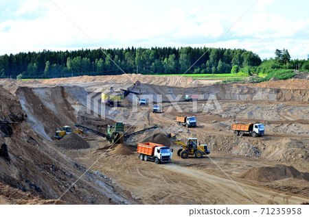Wheel front-end loader loads sand into a dump truck. Wheel front-end loader loads sand into a dump truck. 71235958