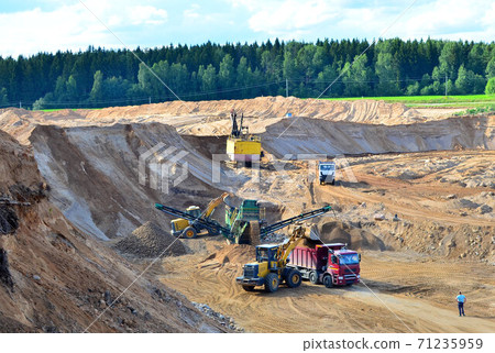 Wheel front-end loader loads sand into a dump truck.  71235959