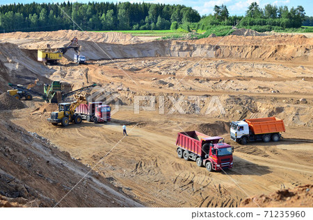 Wheel front-end loader loads sand into a dump truck. Wheel front-end loader loads sand into a dump truck. 71235960