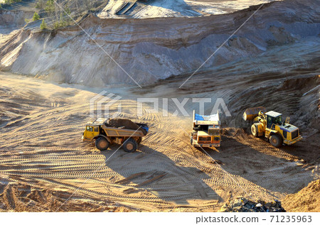 Wheel front-end loader unloading sand into heavy dump truck at the opencast mining quarry 71235963