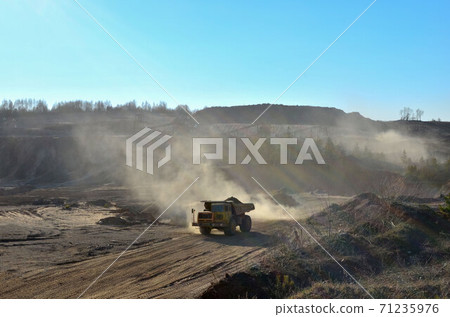 Big yellow mining truck transporting sand in an open-pit mining quarry  71235976