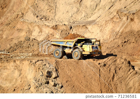 Big yellow dump truck transporting sand in an open-pit mining quarry. Big yellow dump truck transporting sand in an open-pit mining quarry. 71236581