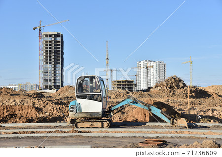Mini excavator dig a trench to lay cables concrete curbs at construction site. Mini excavator dig a trench to lay cables concrete curbs at construction site. 71236609