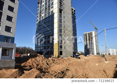 Tower crane constructing a new residential building at a construction site against blue sky Tower crane constructing a new residential building at a construction site against blue sky 71236615