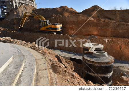 Excavator on earthwork during the laying of pipes of heating system building at construction site. Excavator on earthwork during the laying of pipes of heating system building at construction site. 71236617