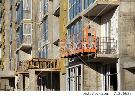 Suspended construction cradle on the background facade of the building. Suspended construction cradle on the background facade of the building. 71236622