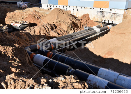 Laying heating pipes in a trench at construction site. Install underground storm systems Laying heating pipes in a trench at construction site. Install underground storm systems 71236623
