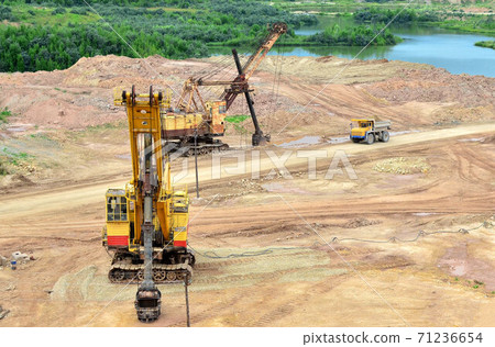 Huge excavators with electric shovel working in the quarry. Big mining trucks transport of minerals in the limestone open-pit mining. Largest dolomite deposit open-cast Gralevo, Belarus, Vitebsk Huge excavators with electric shovel working in the quarry. Big mining trucks transport of minerals in the limestone open-pit mining. Largest dolomite deposit open-cast Gralevo, Belarus, Vitebsk 71236654