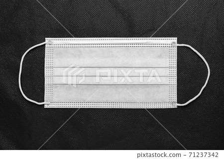 Medical protective face mask on background of non-woven fabric. Flat lay, close-up view of concept global lockdown 71237342