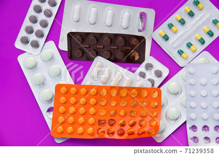 Many colorful tablets and medicines drugs in plastic pharmaceutical packaging on purple background Many colorful tablets and medicines drugs in plastic pharmaceutical packaging on purple background 71239358