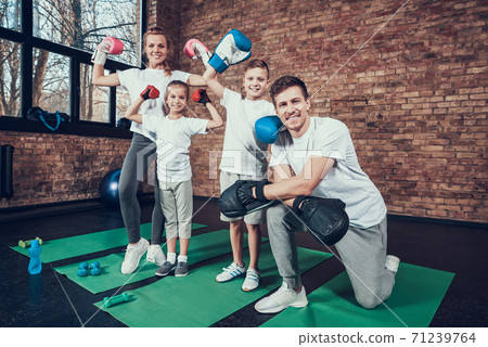 Dad kneels next to children in boxing gloves.  71239764