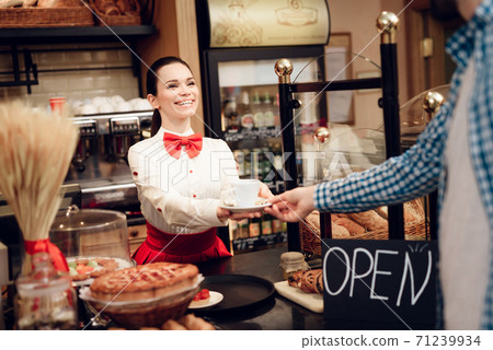 Smiling Girl Giving Cup of Coffee to Young Man. Smiling Girl Giving Cup of Coffee to Young Man. 71239934
