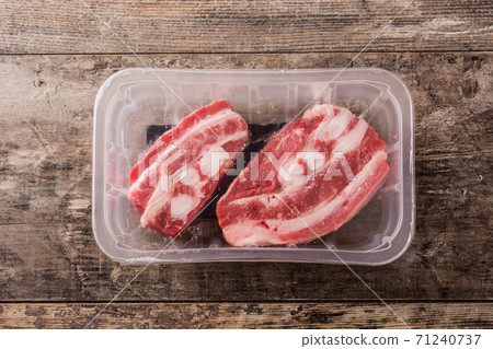 Ribs meat packaged in plastic on wooden table. Top view 71240737