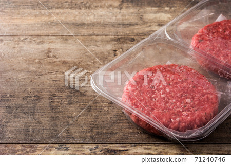 burger meat packaged in plastic on wooden table. Copy space 71240746