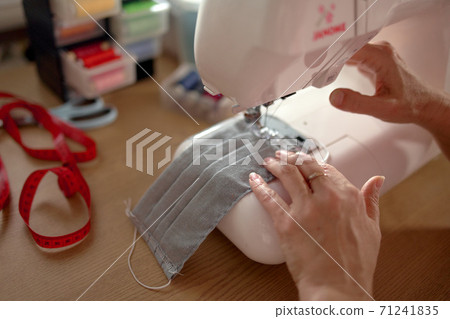 Woman hands using the sewing machine to sew the face mask Woman hands using the sewing machine to sew the face mask 71241835