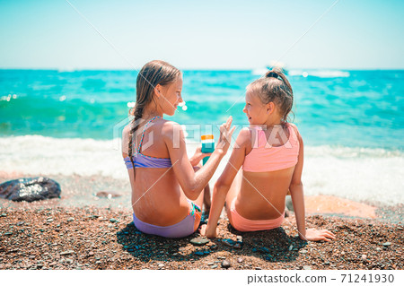 UV protection. Sister puts sunscreen on her little sister's nose 71241930