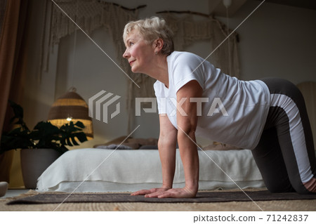 Caucasian woman on mat doing cat stretch posture for spine. Caucasian woman on mat doing cat stretch posture for spine. 71242837