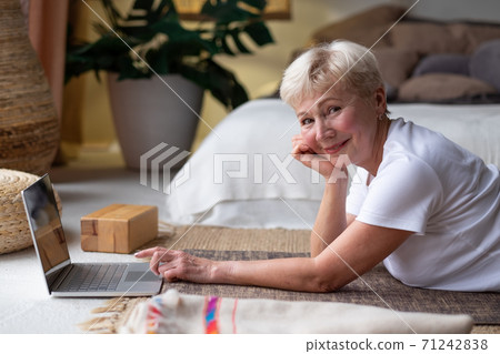 Active senior woman surfing in internet on yoga mat. 71242838