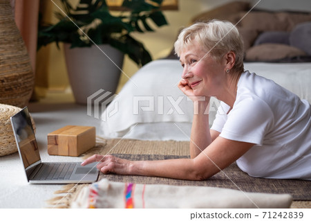 Active senior woman surfing in internet on yoga mat. 71242839