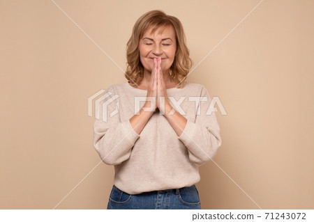 Elderly woman keeps palms in pray gesture, closes eyes, prays and asks God for health Elderly woman keeps palms in pray gesture, closes eyes, prays and asks God for health 71243072