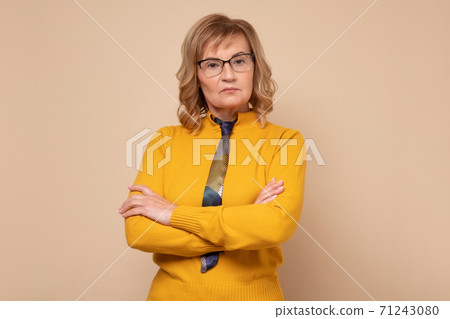 Serious caucasian woman in glasses standing with folded hands and looking at camera Serious caucasian woman in glasses standing with folded hands and looking at camera 71243080