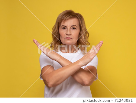Mature woman making X sign with crossed hands, gesturing stop, warning of danger. Mature woman making X sign with crossed hands, gesturing stop, warning of danger. 71243081