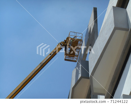 SELANGOR, MALAYSIA -FEBRUARY 16, 2017: Construction workers using mobile crane bucket while working at high level in the construction site. The bucket movement control by the workers himself. SELANGOR, MALAYSIA -FEBRUARY 16, 2017: Construction workers using mobile crane bucket while working at high level in the construction site. The bucket movement control by the workers himself. 71244122