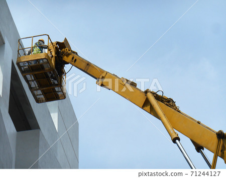 SELANGOR, MALAYSIA -FEBRUARY 16, 2017: Construction workers using mobile crane bucket while working at high level in the construction site. The bucket movement control by the workers himself.  71244127