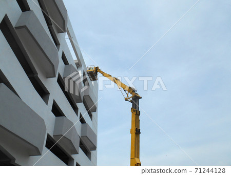 SELANGOR, MALAYSIA -FEBRUARY 16, 2017: Construction workers using mobile crane bucket while working at high level in the construction site. The bucket movement control by the workers himself. SELANGOR, MALAYSIA -FEBRUARY 16, 2017: Construction workers using mobile crane bucket while working at high level in the construction site. The bucket movement control by the workers himself. 71244128
