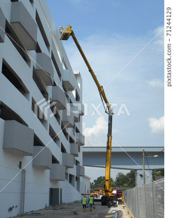 SELANGOR, MALAYSIA -FEBRUARY 16, 2017: Construction workers using mobile crane bucket while working at high level in the construction site. The bucket movement control by the workers himself. SELANGOR, MALAYSIA -FEBRUARY 16, 2017: Construction workers using mobile crane bucket while working at high level in the construction site. The bucket movement control by the workers himself. 71244129