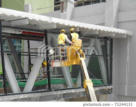 SELANGOR, MALAYSIA -FEBRUARY 16, 2017: Construction workers using mobile crane bucket while working at high level in the construction site. The bucket movement control by the workers himself. SELANGOR, MALAYSIA -FEBRUARY 16, 2017: Construction workers using mobile crane bucket while working at high level in the construction site. The bucket movement control by the workers himself. 71244131