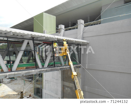 SELANGOR, MALAYSIA -FEBRUARY 16, 2017: Construction workers using mobile crane bucket while working at high level in the construction site. The bucket movement control by the workers himself.  71244132