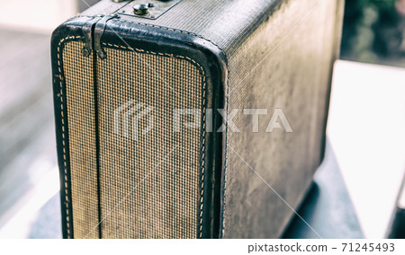 Gray suitcase with fabric pattern and leather handle close up on a blurred background Gray suitcase with fabric pattern and leather handle close up on a blurred background 71245493