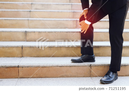 The businessman is walking up the stairs, he has a lot of knee pain. 71251195