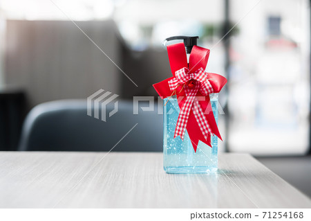 Merry Christmas with wash hand sanitizer gel bottle against coronavirus or Corona Virus Disease (Covid-19) at office Indoor. Holiday, Hygiene, New Normal and Healthcare concept Merry Christmas with wash hand sanitizer gel bottle against coronavirus or Corona Virus Disease (Covid-19) at office Indoor. Holiday, Hygiene, New Normal and Healthcare concept 71254168