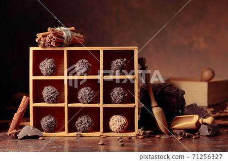 Chocolate candy in wooden box, broken pieces of chocolate, cinnamon sticks, anise and coffee beans. 71256327
