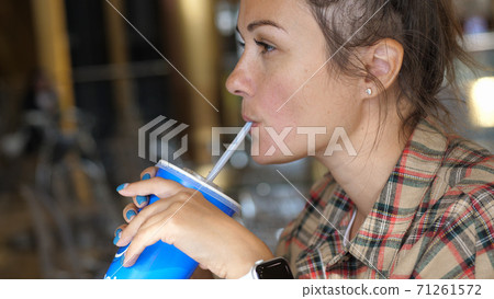 Young woman enjoying a drink with the straw. Drinking cola or soda pop with a straw. Close up portrait shot. 71261572