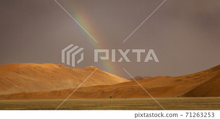 Rainbow shines over a sand dune in the desert 71263253