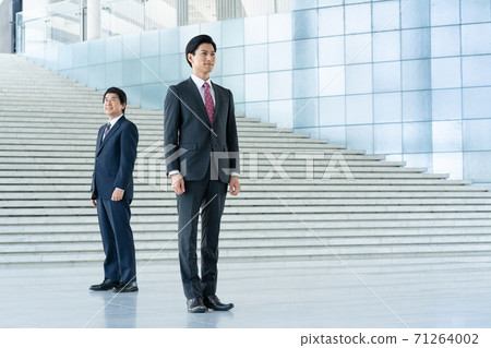 A young man and a middle-aged man standing in the lobby of a business company A young man and a middle-aged man standing in the lobby of a business company 71264002