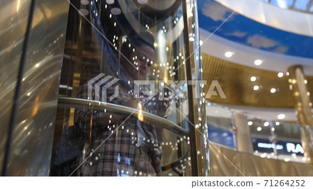 Attractive brunette business lady in modern steel elevator in large office center and uses mobile phone. Attractive brunette business lady in modern steel elevator in large office center and uses mobile phone. 71264252