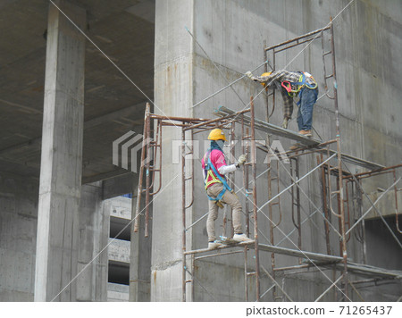 JOHOR, MALAYSIA -SEPTEMBER 05, 2016: Construction workers wearing safety harness and adequate safety gear and climbing the scaffolding while working at high level.  71265437