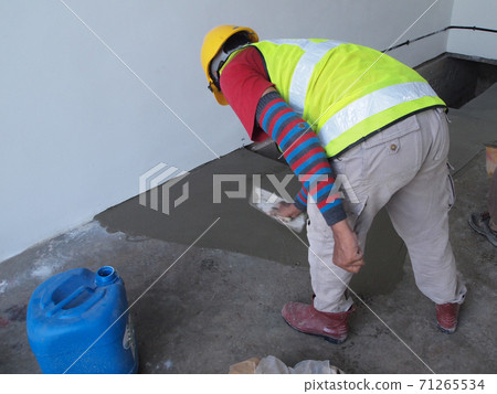 JASIN, MALAYSIA -SEPTEMBER 05, 2016: Construction workers leveling wet cement as the floor finishes on top of cement screed surface.  71265534