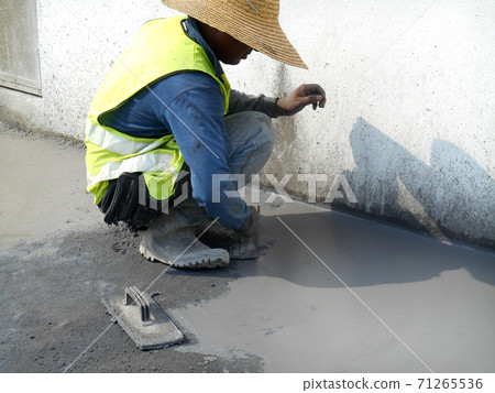 JASIN, MALAYSIA -SEPTEMBER 05, 2016: Construction workers leveling wet cement as the floor finishes on top of cement screed surface.  71265536